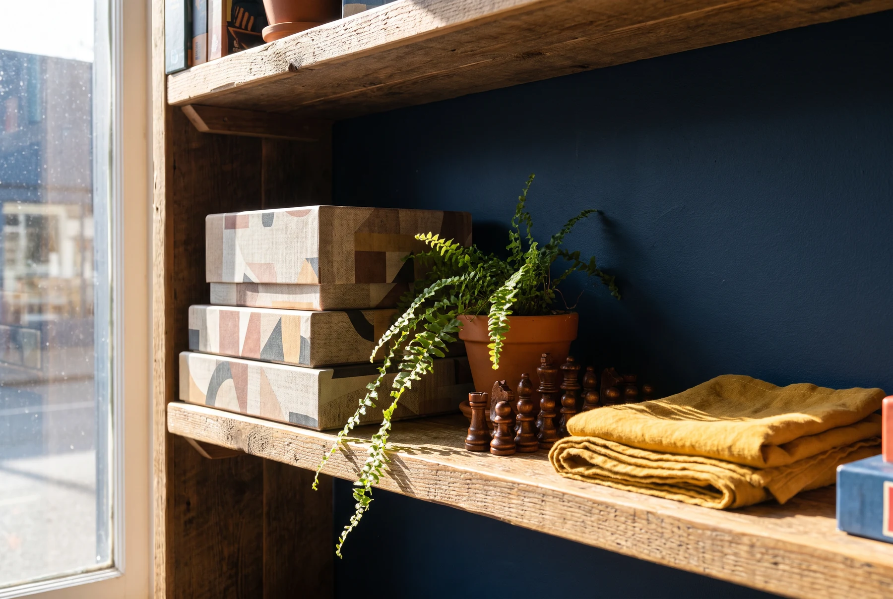 A shelf with abstract game boxes, wooden pieces and a folded yellow cloth